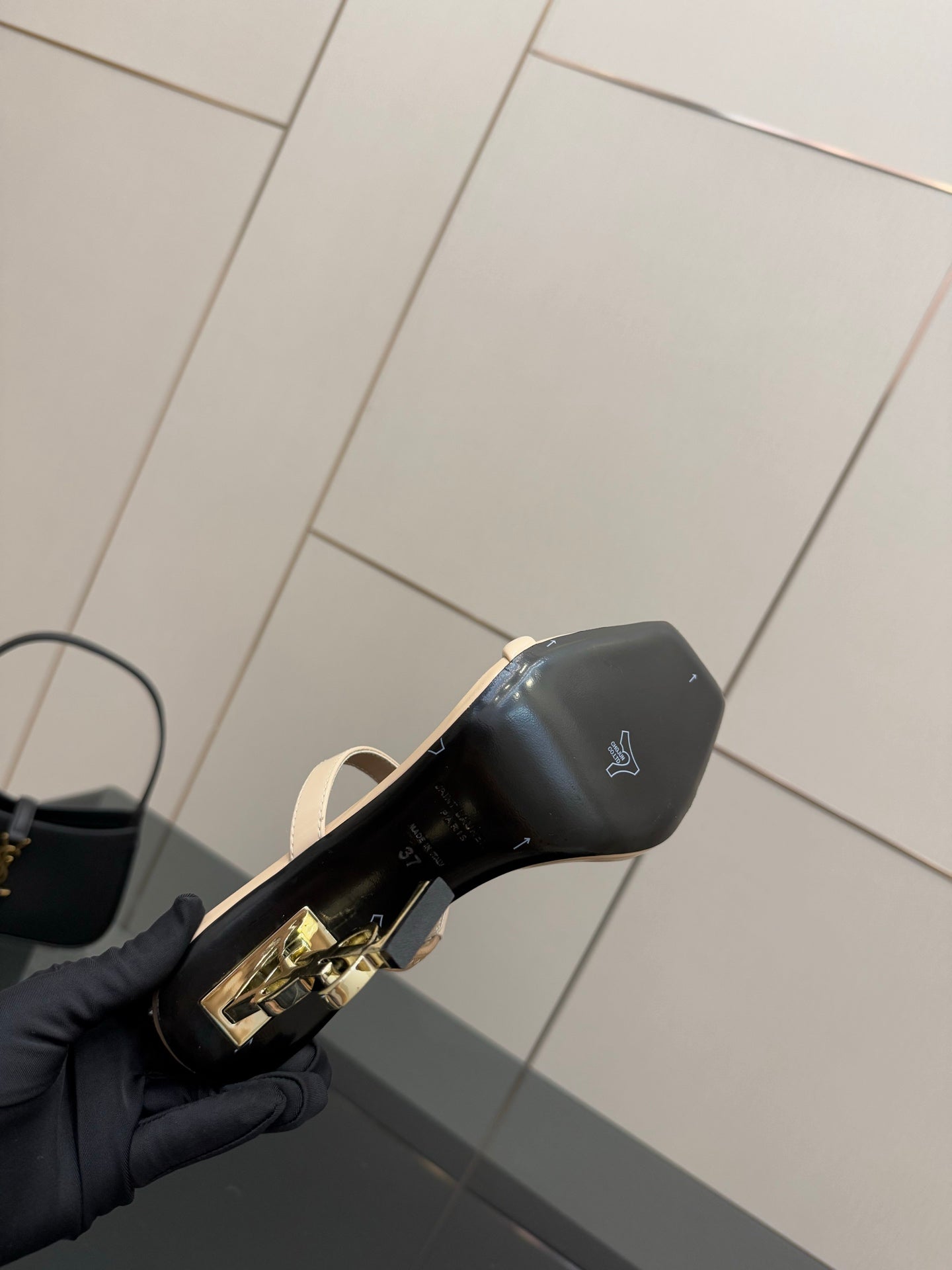 Two-tone heeled mule sandal showing black heel cap and gold logo hardware
