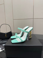 Mint green heeled mule sandals with open toe and gold logo detail on heel