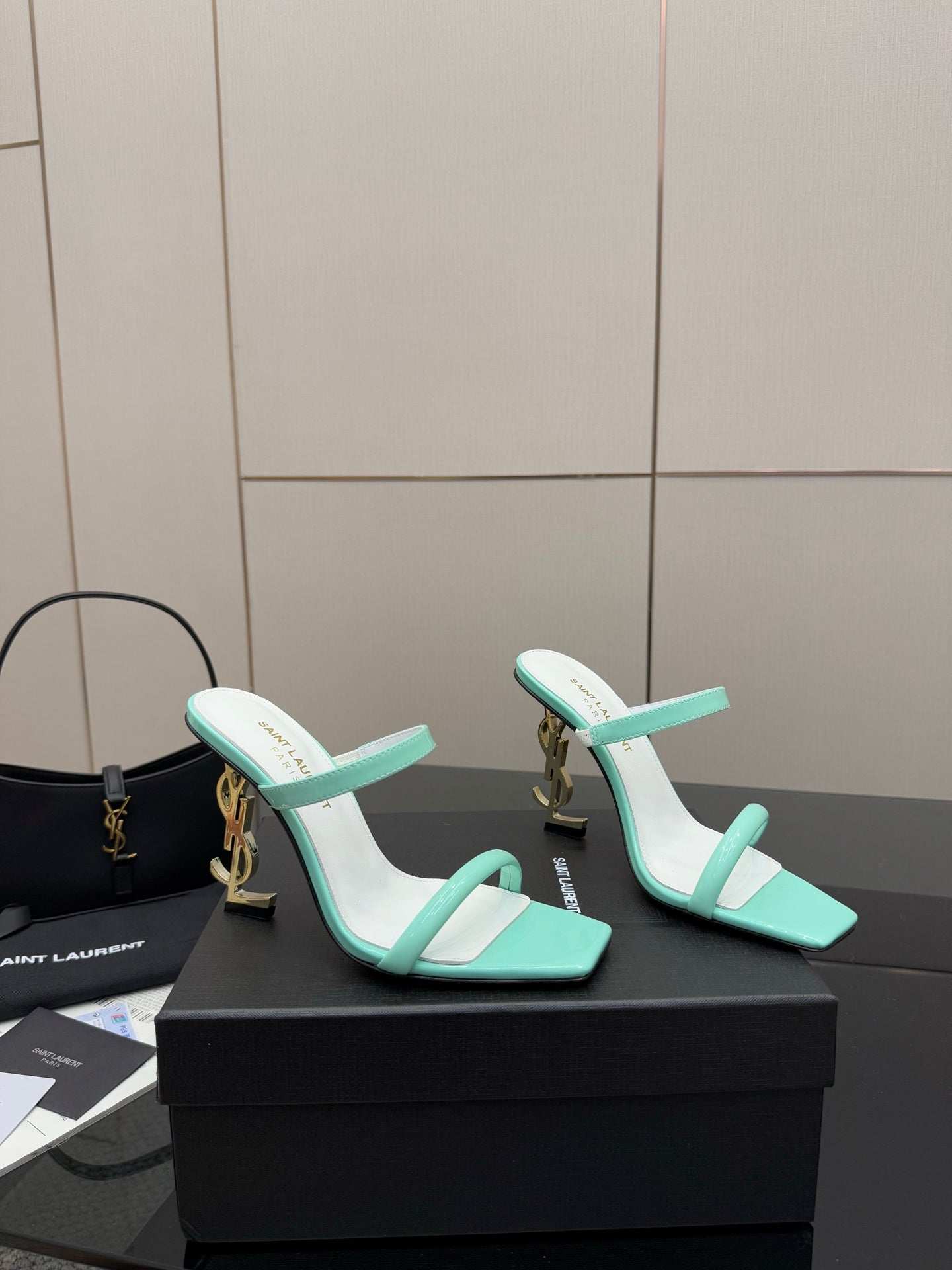 Mint green heeled mule sandals with two straps and gold logo charm on heel