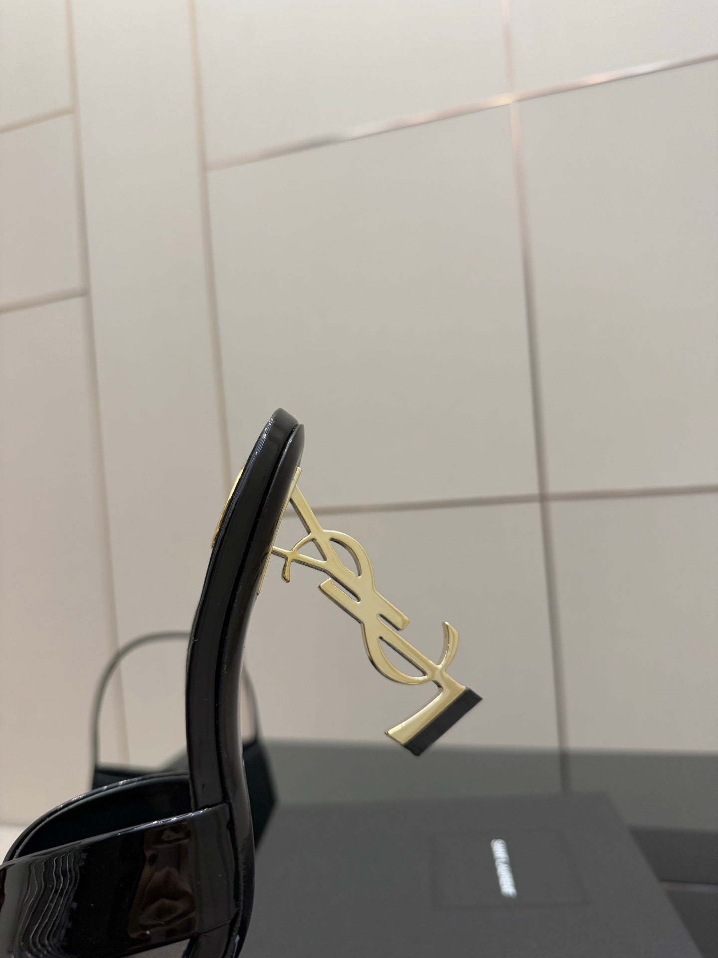 Black patent mule heel with gold logo emblem on the side