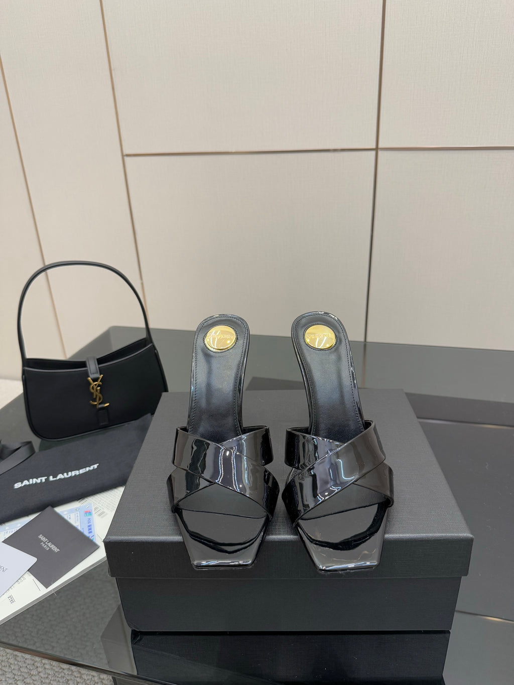 Black patent mule heels with open toe, platform base, and gold logo details