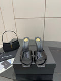 Black patent mule heels with open toe, platform base, and gold logo details