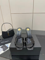 Black patent mule heels with open toe, platform base, and gold logo details