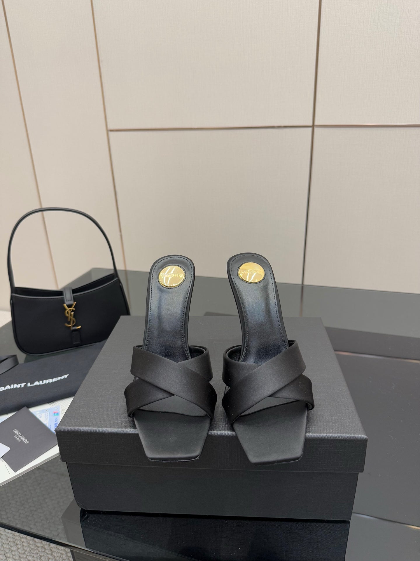 Black heeled mule sandals with black straps and gold YSL logo on the heel