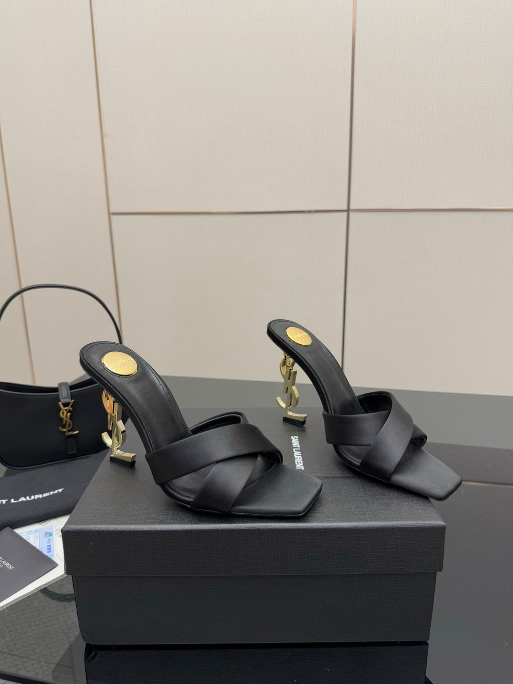 Black heeled mule sandals with wide crossover straps and gold YSL logo detailing