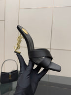 Close side view: black heeled mule sandal with crossover straps and gold YSL heel emblem