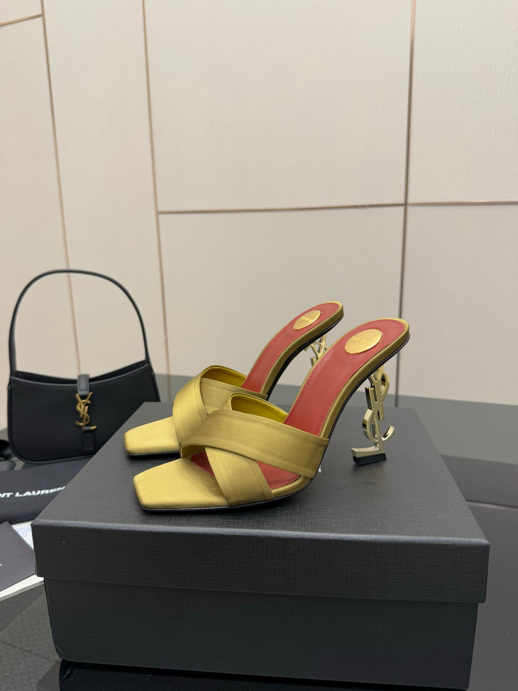 Pair of yellow mule sandals with red lining and gold chain logo heel