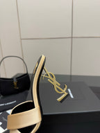 Heeled mule sandal with cream strap, dark sole, and gold YSL logo detail on heel.