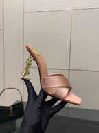 Pink YSL logo slide sandals, side profile showing gold chain-style emblem
