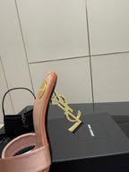 Pink YSL logo slide sandals, close-up of gold heel emblem and open toe
