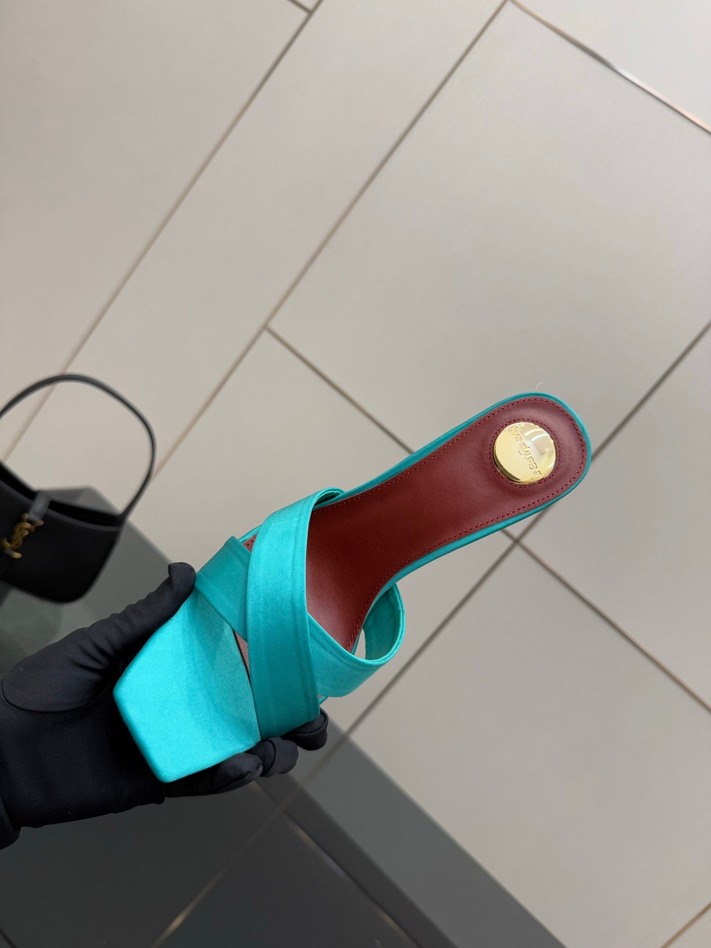 Teal YSL mule sandal sole view, red-brown footbed and round gold logo patch