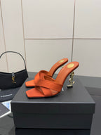 YSL orange mule sandals with open toe, crisscross strap, and gold logo heel detail