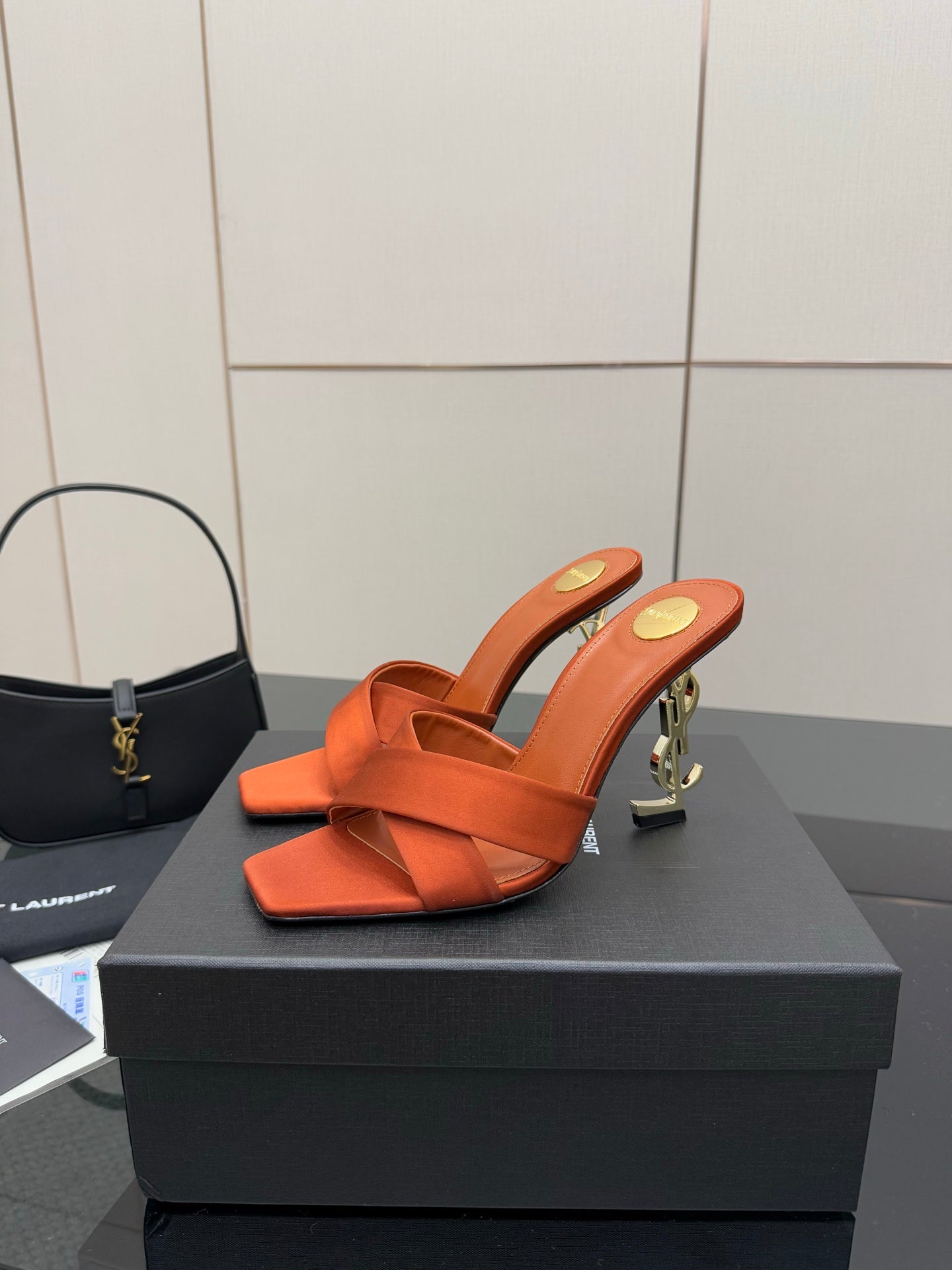 YSL orange mule sandals with open toe, crisscross strap, and gold logo heel detail
