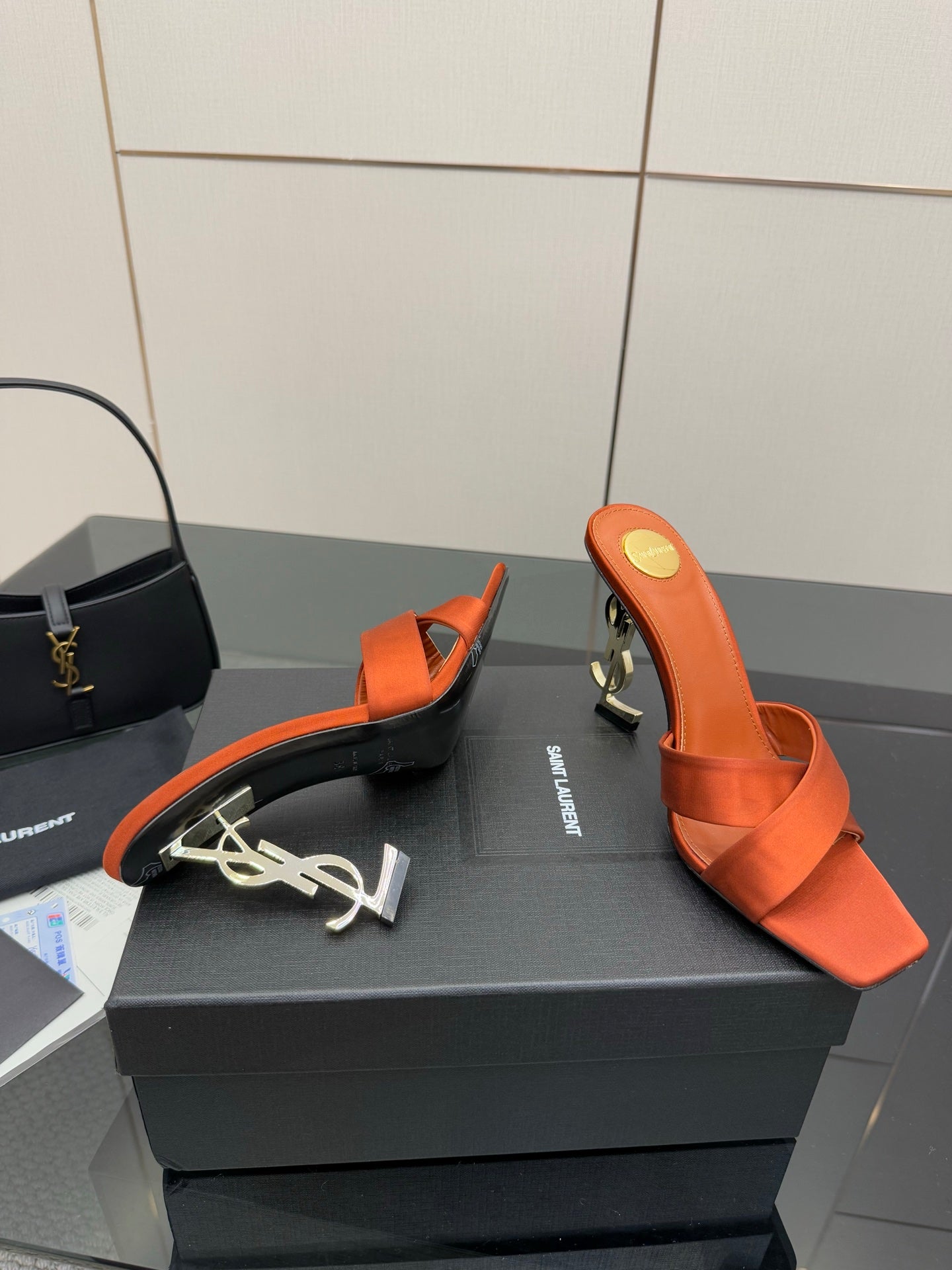 YSL orange mule sandals with open toe and crisscross straps, viewed side angle