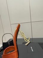 YSL orange mule sandal close-up, gold logo on curved heel and open toe front