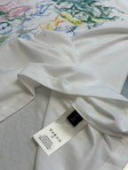 White T-shirt with care label on inner seam and multicolor print at top