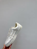 White sneakers held up, showing side profile with raised stripe detail