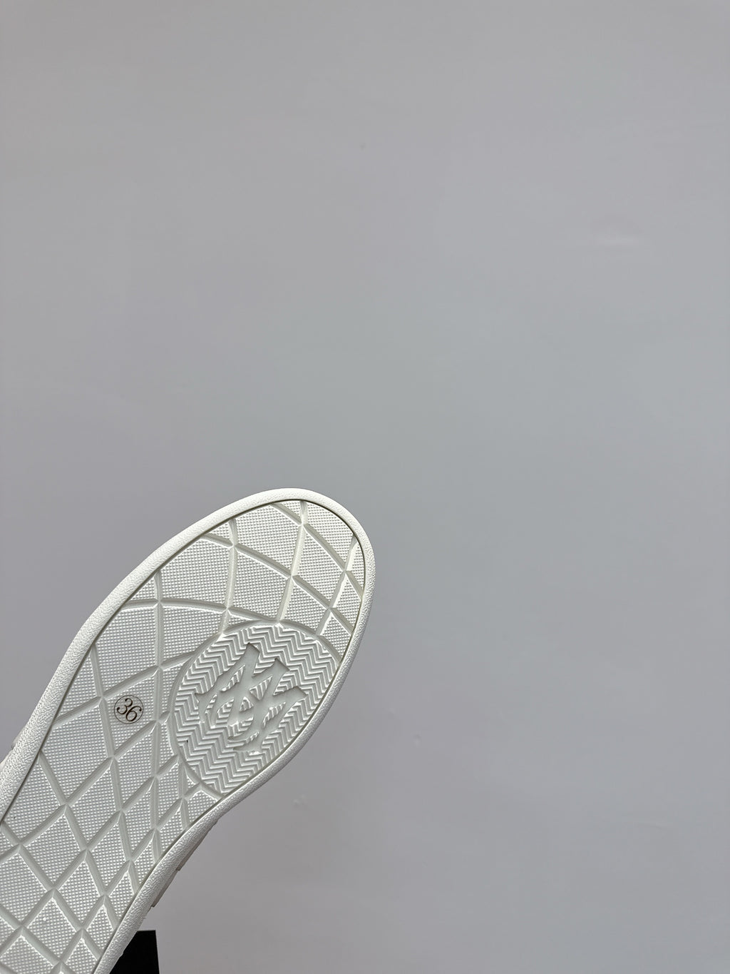 White sneaker outsole close-up with grid pattern and embossed markings