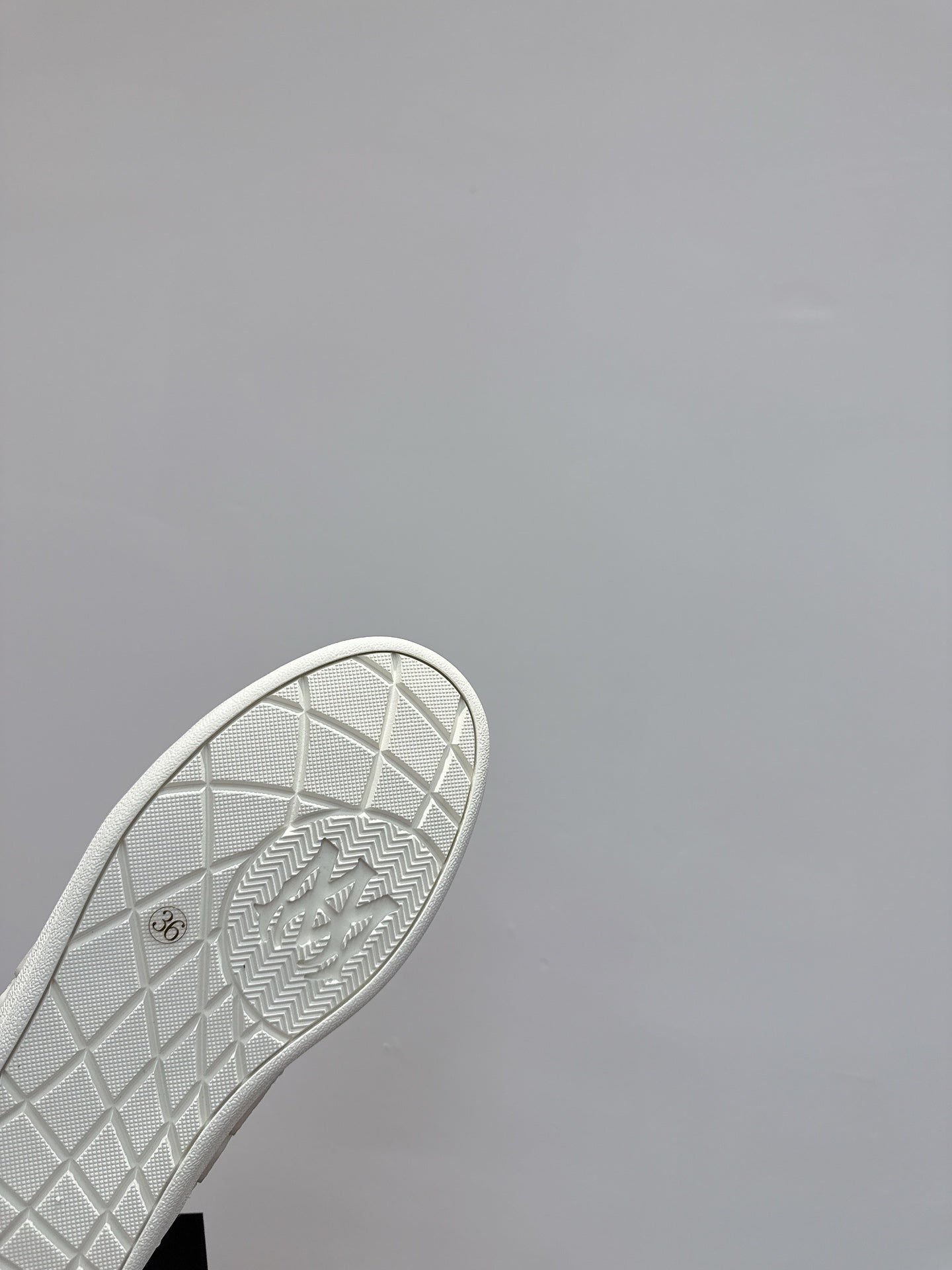 White sneaker outsole close-up with grid pattern and embossed markings