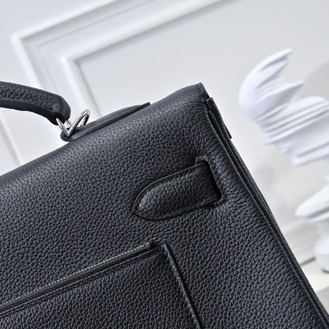 Black pebbled leather handbag with flap clasp and stitched panel detail