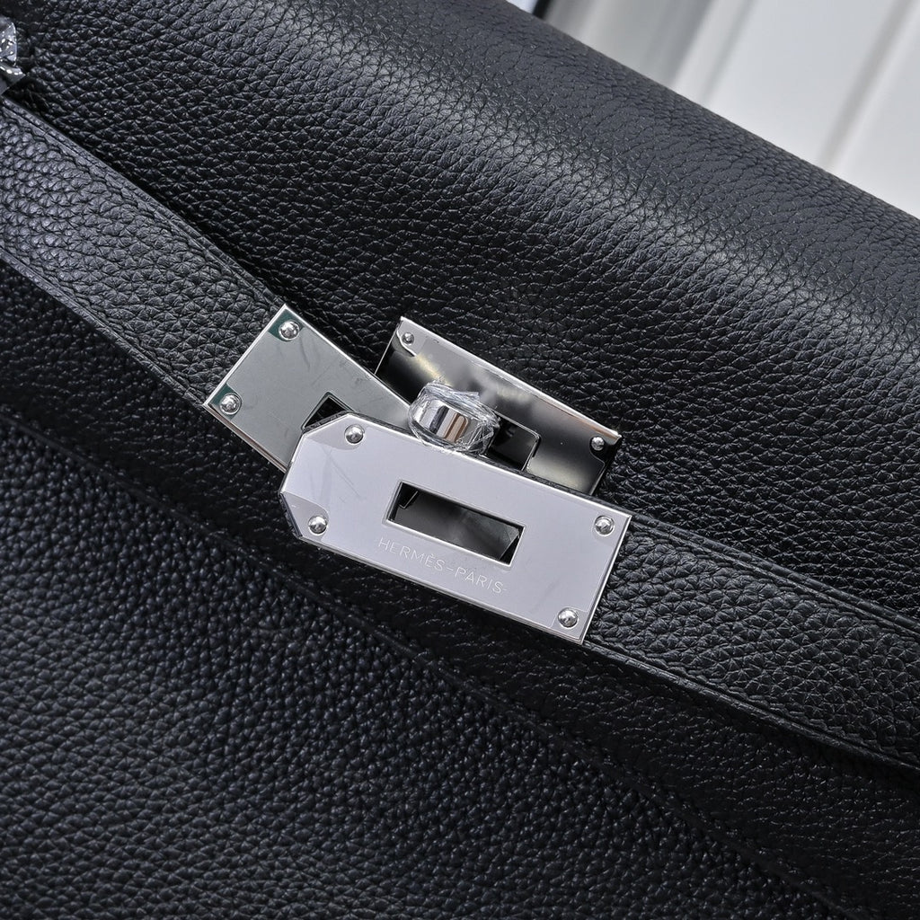 Silver metal clasp on black pebbled leather handbag with stitched strap edges
