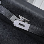 Silver metal clasp on black pebbled leather handbag with stitched strap edges