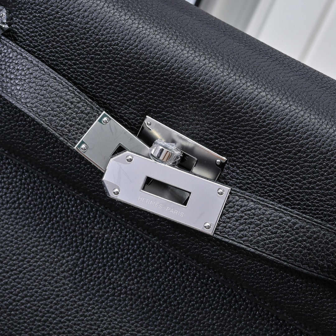 Silver metal clasp on black pebbled leather handbag with stitched strap edges