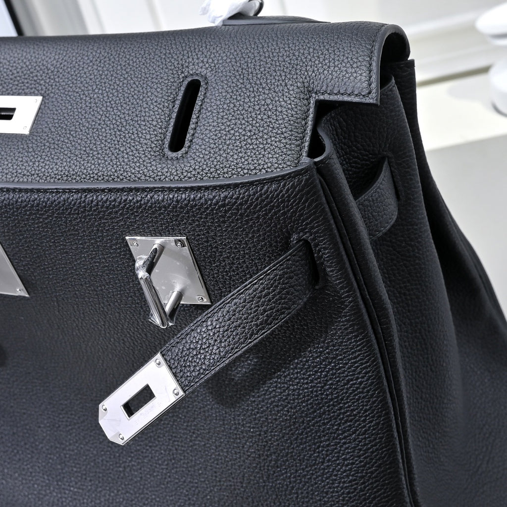 Black pebbled leather handbag detail with silver hardware plaques and cutout handle