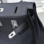Black pebbled leather handbag detail with silver hardware plaques and cutout handle
