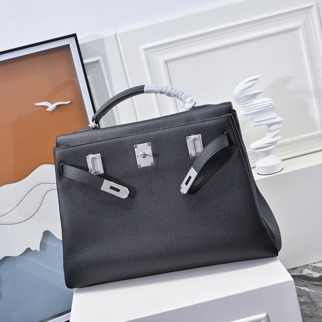 Black leather handbag with top handle, front buckle pieces and silver lock hardware