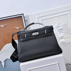 Black leather handbag with top handle, shoulder strap and front clasp bar hardware