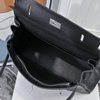 Black leather handbag interior with zipper pocket and adjustable shoulder strap, silver rings