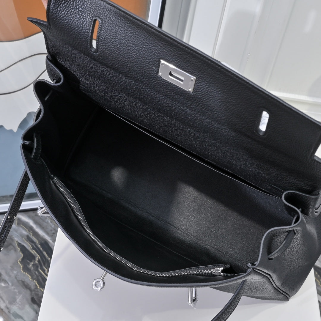 Black leather handbag interior with zipper pocket and adjustable shoulder strap, silver rings