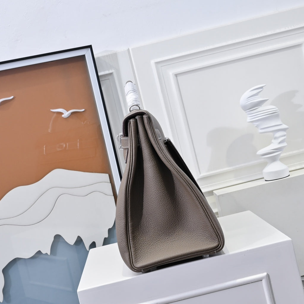 Hermes handbag in taupe textured leather, side view with top handle and shoulder strap