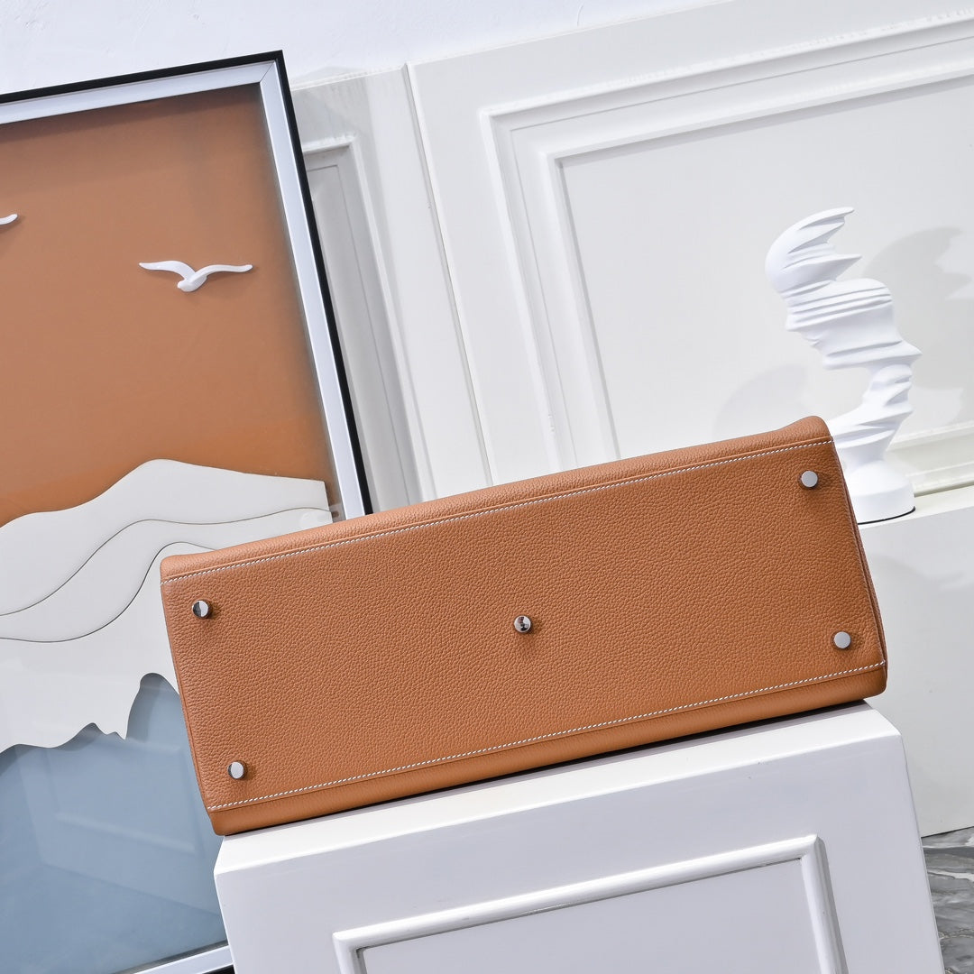 Hermes leather bag in tan-brown with long front flap and silver-toned studs.