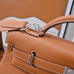 Hermes leather bag in tan-brown with detachable strap hardware and front pocket stitching.