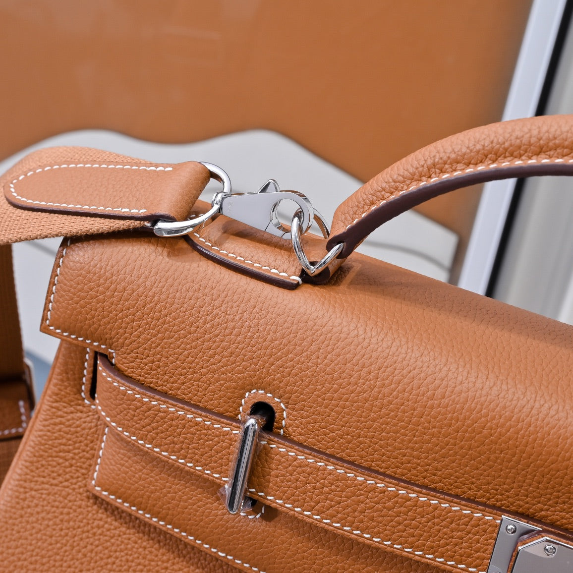 Hermes leather bag in tan-brown with detachable strap hardware and front pocket stitching.