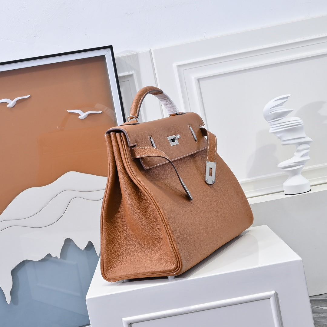 Hermes leather bag in tan-brown with structured top handle and front clasp hardware.