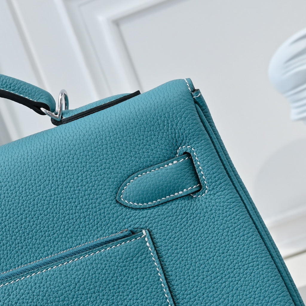 Turquoise leather handbag close-up of stitched flap pocket detail and trim