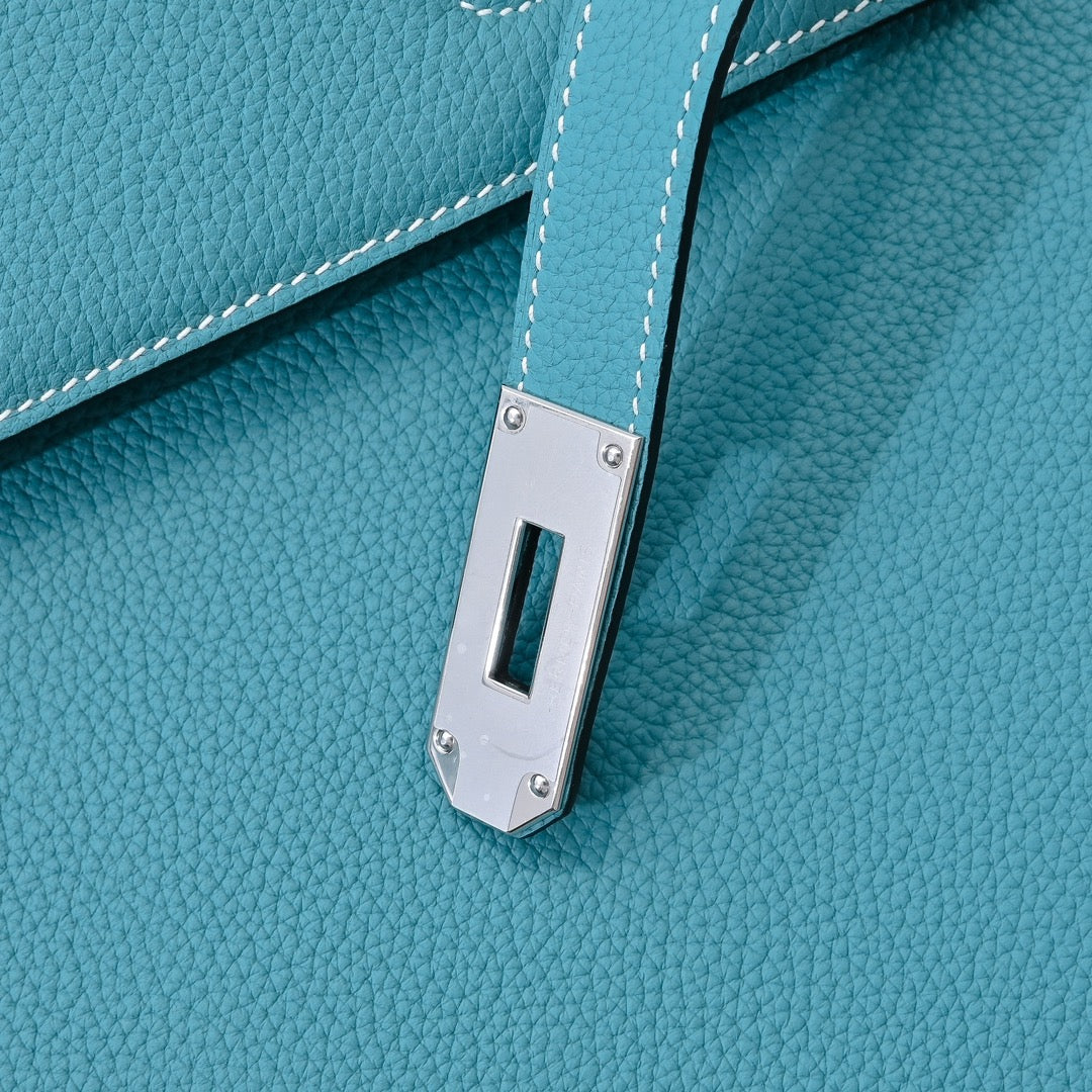 Turquoise leather handbag close-up of front turn-lock hardware and stitching