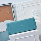 Turquoise leather handbag with long front flap, metal feet studs at corners