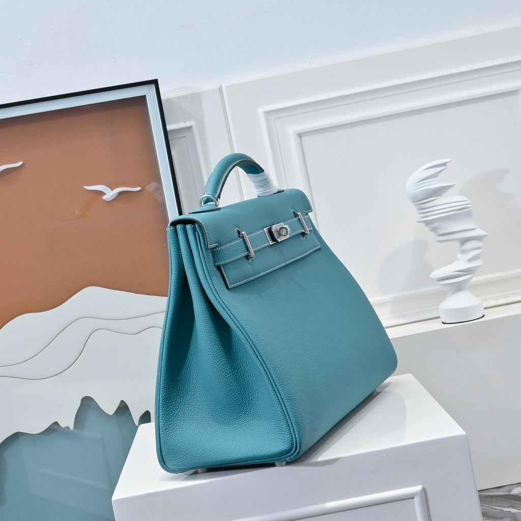 Turquoise leather handbag with short top handle and front flap, standing upright