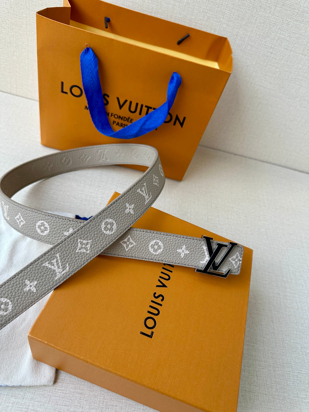 Gray monogram belt on white pouch, LV buckle and keepers visible