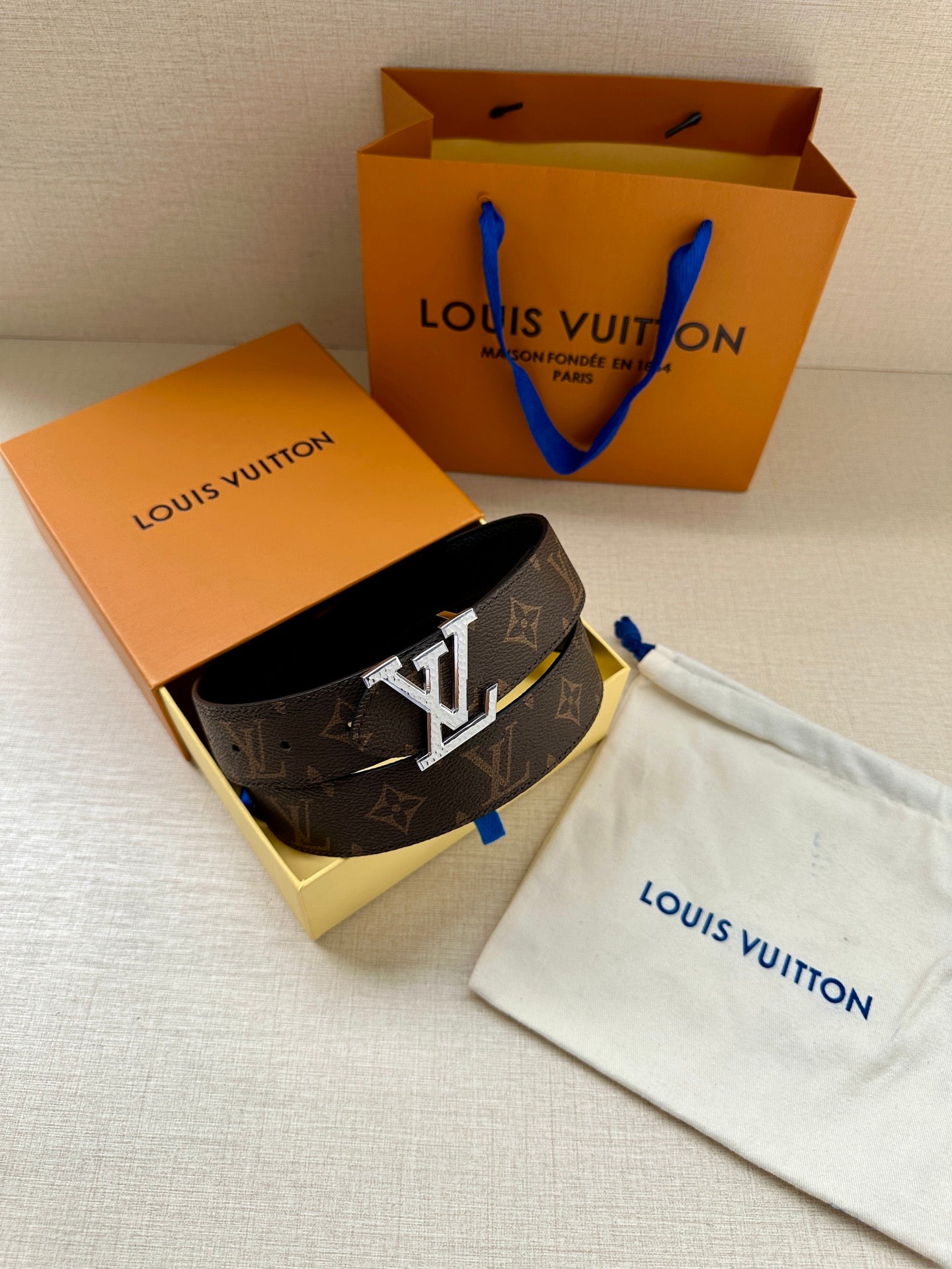 Brown monogram belt with silver-tone LV buckle, placed in box with dust bag.
