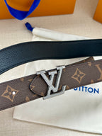 Monogram belt close-up with silver-tone LV buckle on dark strap.