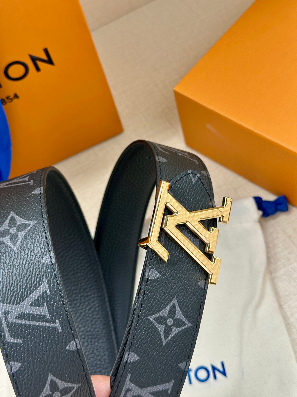 Louis Vuitton belt end with dark monogram canvas and gold geometric LV buckle