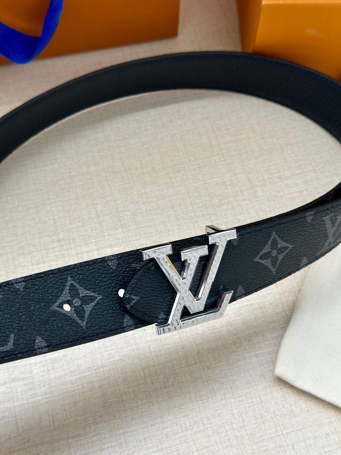 Louis Vuitton belt with dark monogram canvas and large silver LV buckle closeup