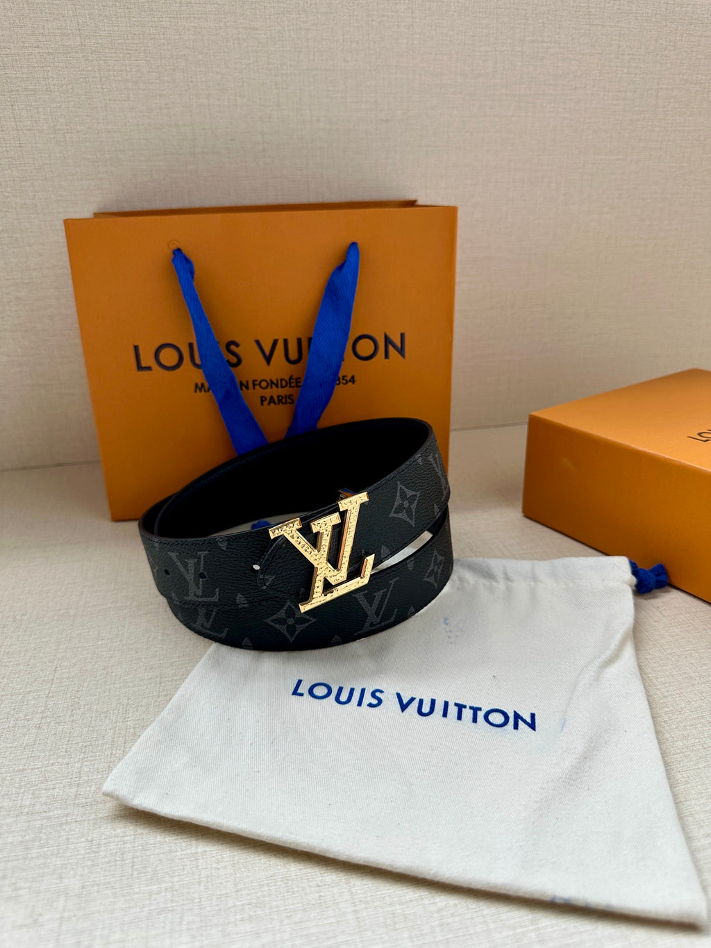 Louis Vuitton belt with dark monogram canvas and gold LV buckle on dust bag