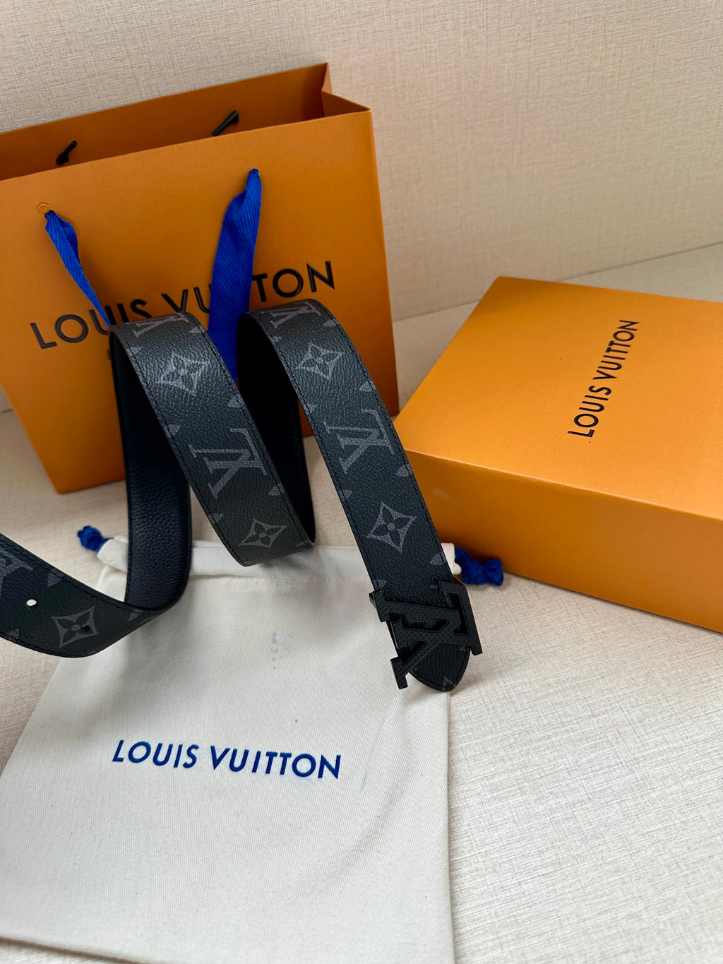Louis Vuitton belt with dark monogram strap and gold-tone LV buckle, flat lay