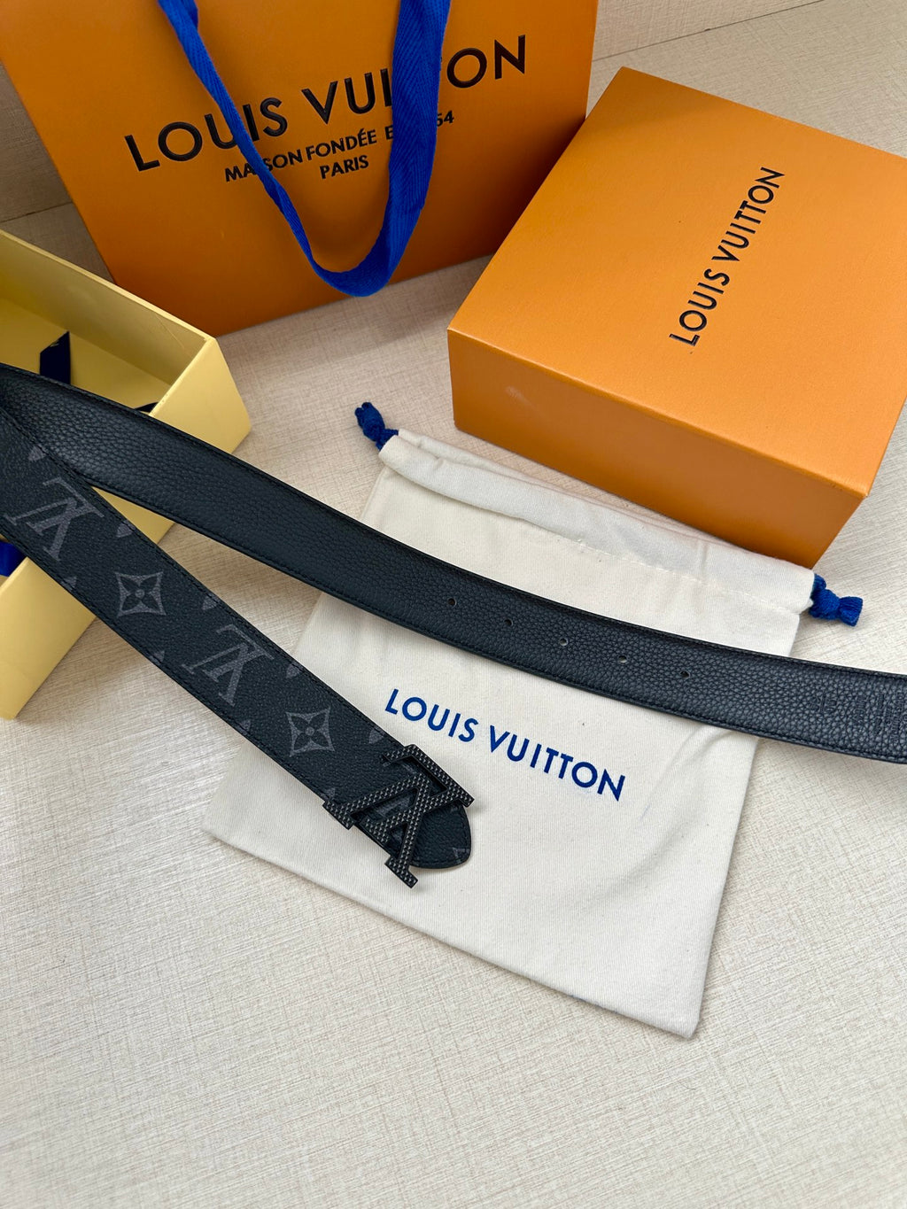 Louis Vuitton monogram belt on dust bag, dark strap with gold-tone buckle